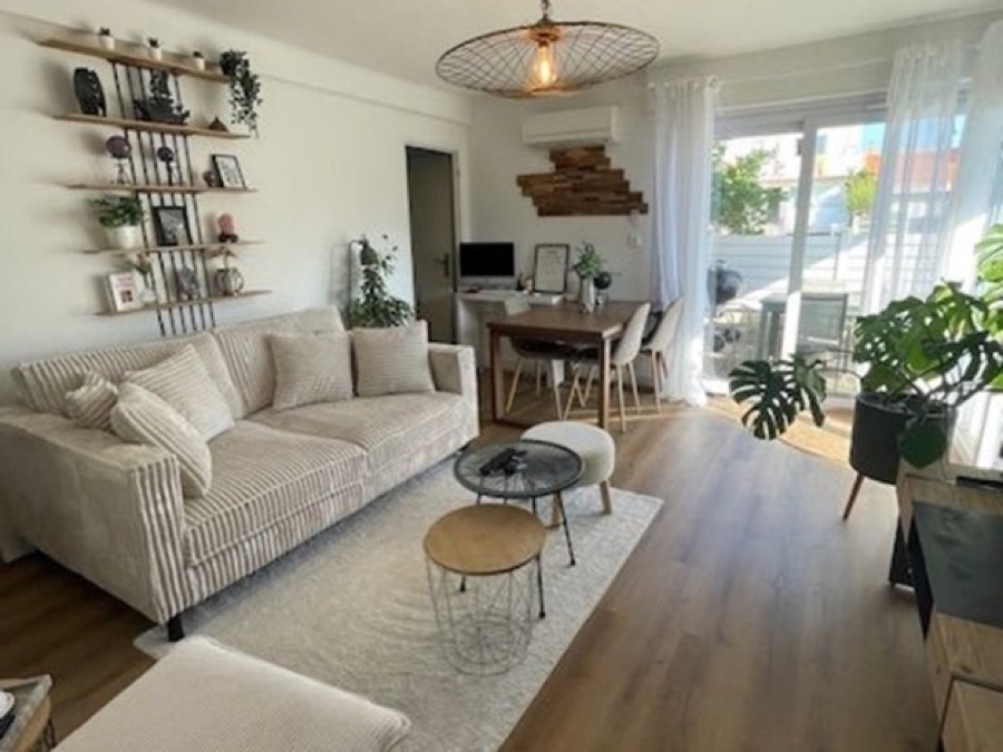 Séjour rénové de l'appartement de Palavas-les-Flots, canapé clair et coin repas devant la baie vitrée