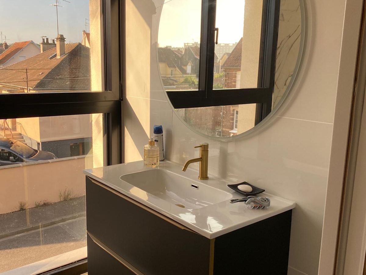 Salle de bain rénovée avec meuble suspendu et miroir rond